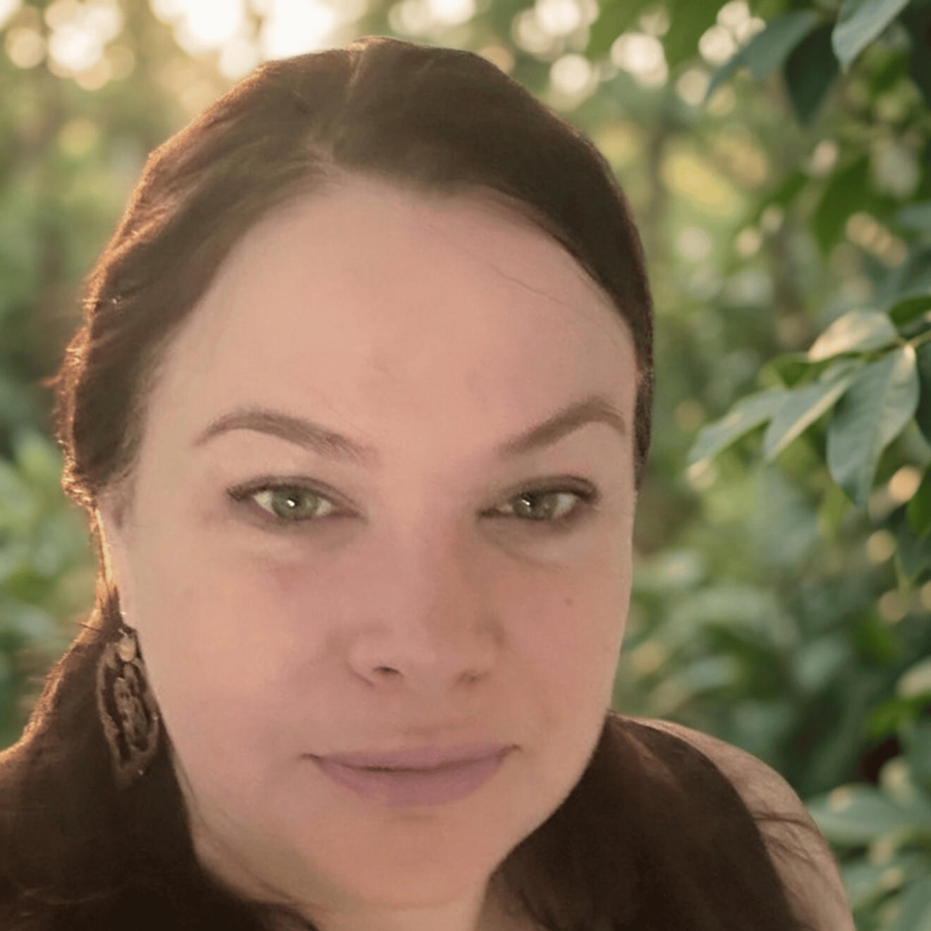 Photo of Caroline Jane Caroline Jane, Emotion Code and Body Code practitioner, outdoors under green foliage